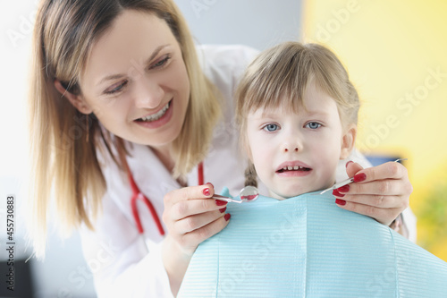 Little cute scared girl sitting in chair at dentist closeup