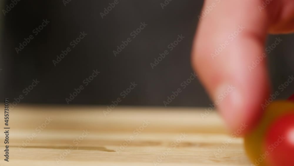 Professional chef cutting cherry tomato on wooden cutting board close-up. Cooking dishes with vegetables, using sharp kitchen knife. Salad made of tomatoes. Professional chef cutting cherry tomato on wooden cutting board close-up. Cooking dishes with vegetables, using sharp kitchen knife. Salad made of tomatoes.