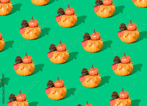 Creative autumn pattern made of pumpkins, pine cones and leaves on green background. Minimal seasonal concept. Halloween or Thanksgiving composition.