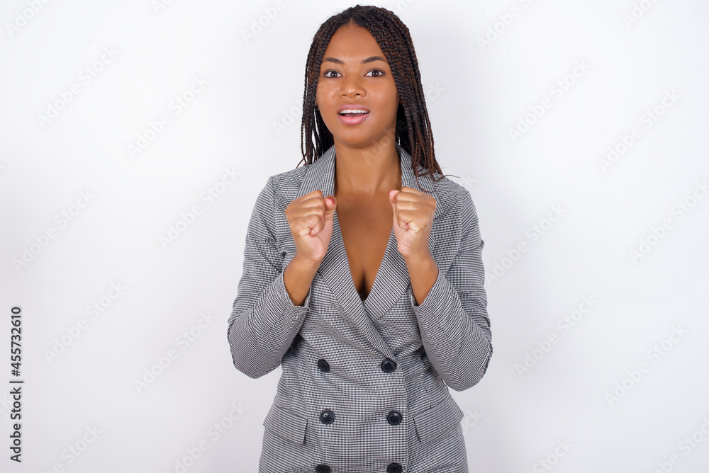 Portrait of desperate and shocked Young african american business woman with braids over white wall looking panic, holding hands near face, with mouth wide open. Portrait of desperate and shocked Young african american business woman with braids over white wall looking panic, holding hands near face, with mouth wide open.
