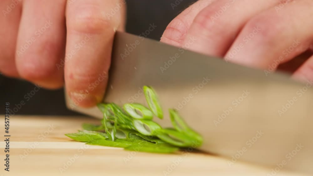Professional chef cutting green onion on wooden cutting board close-up. Cooking dishes with greenery, using sharp kitchen knife. Professional chef cutting green onion on wooden cutting board close-up. Cooking dishes with greenery, using sharp kitchen knife.