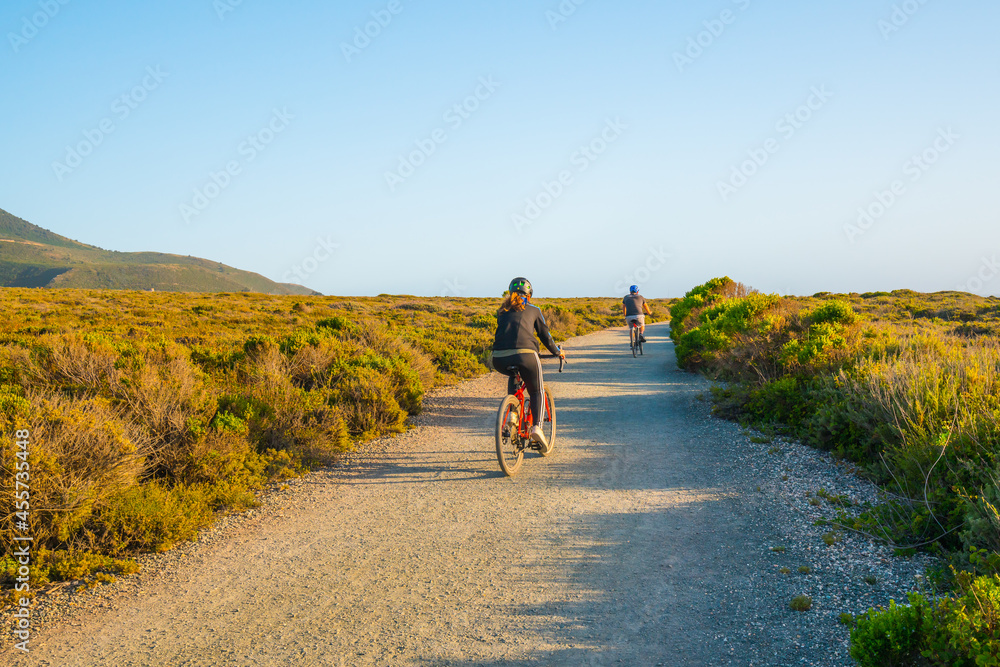 Young couple cycling on rural road in Montana de Oro State Park, Los Osos, California Central Coast Young couple cycling on rural road in Montana de Oro State Park, Los Osos, California Central Coast