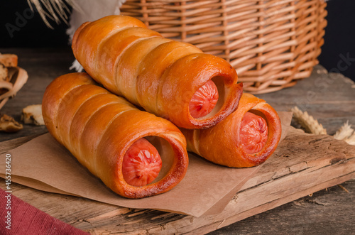 Appetizing fresh culinary pastry - sausages in pastry on wooden photo