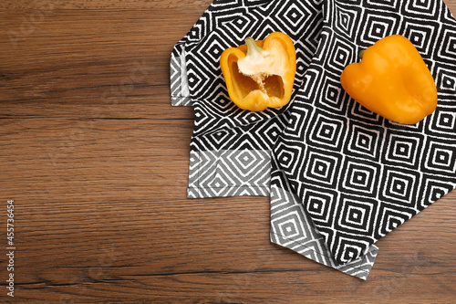 Kitchen towel and bell peppers on wooden table, flat lay. Space for text