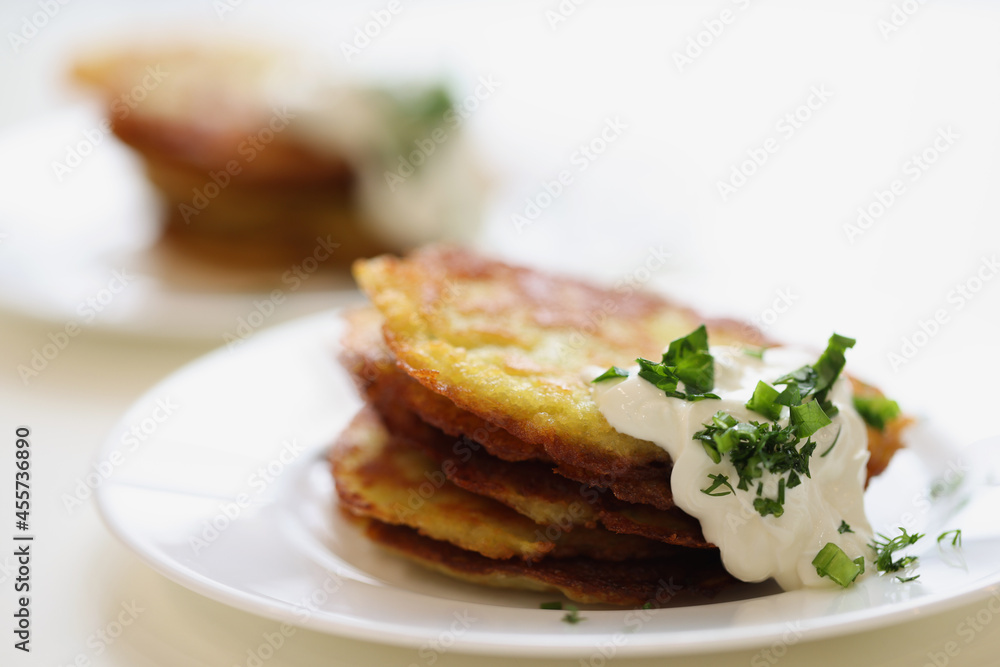 Potato pancakes with sour cream and herbs on plate Potato pancakes with sour cream and herbs on plate