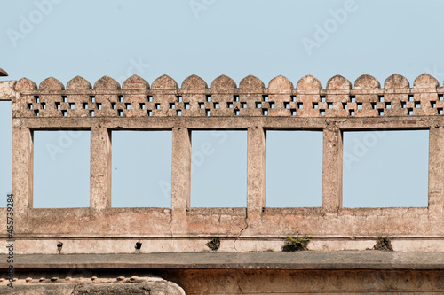 Geometric architectural detail of rectangular windows on the walls of a roof in an ancient palace with a blue sky in background in Orchha in India.
