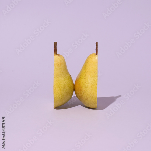 Creative minimal design with cut yellow pear on purple background. 