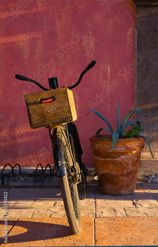 Beautiful side light falls on a vintage, black bike with a wooden crate carrier is parked in a rack on a street in Loreto, Mexico 