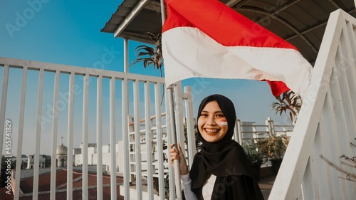 Woman in a hijab sitting on staircase holding Indonesian flag photo