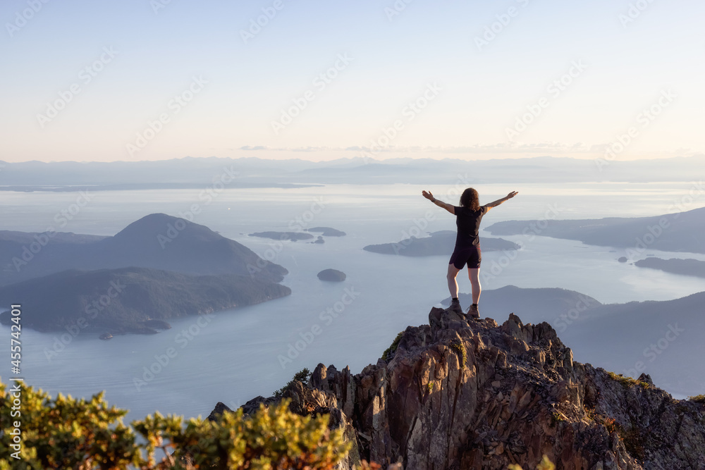 Adventurous Caucasian Woman Hiking on top of a Rocky Mountain Cliff. Sunny Summer Sunset. Mnt Brunswick Hike, North of Vancouver, British Columbia, Canada. Adventurous Caucasian Woman Hiking on top of a Rocky Mountain Cliff. Sunny Summer Sunset. Mnt Brunswick Hike, North of Vancouver, British Columbia, Canada.