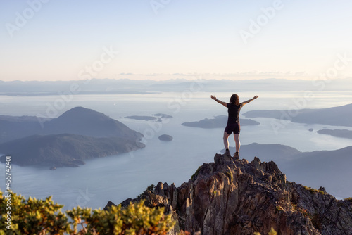 Adventurous Caucasian Woman Hiking on top of a Rocky Mountain Cliff. Sunny Summer Sunset. Mnt Brunswick Hike, North of Vancouver, British Columbia, Canada. © edb3_16