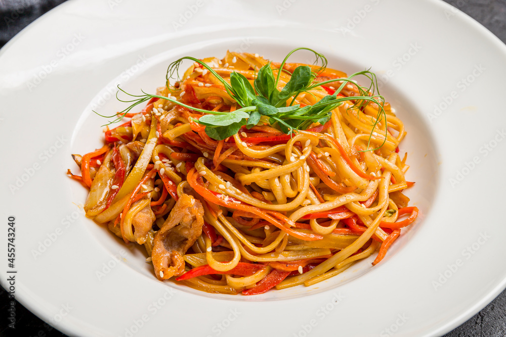 Udon noodles with chicken and vegetables on white plate, chinese cuisine close up macro