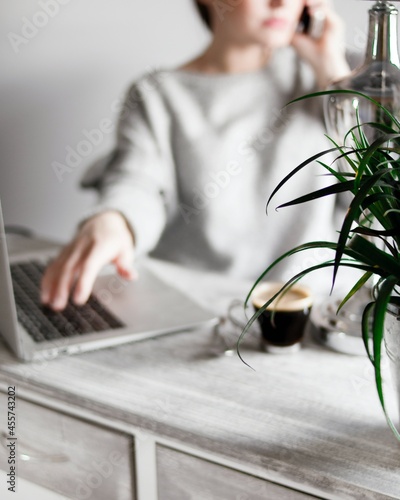 Woman working on laptop while talking on the phone photo