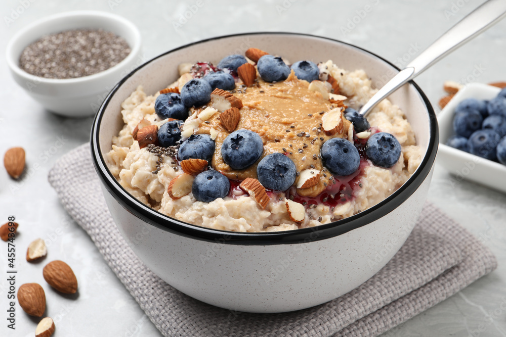 Tasty oatmeal porridge with toppings served on light grey table Tasty oatmeal porridge with toppings served on light grey table
