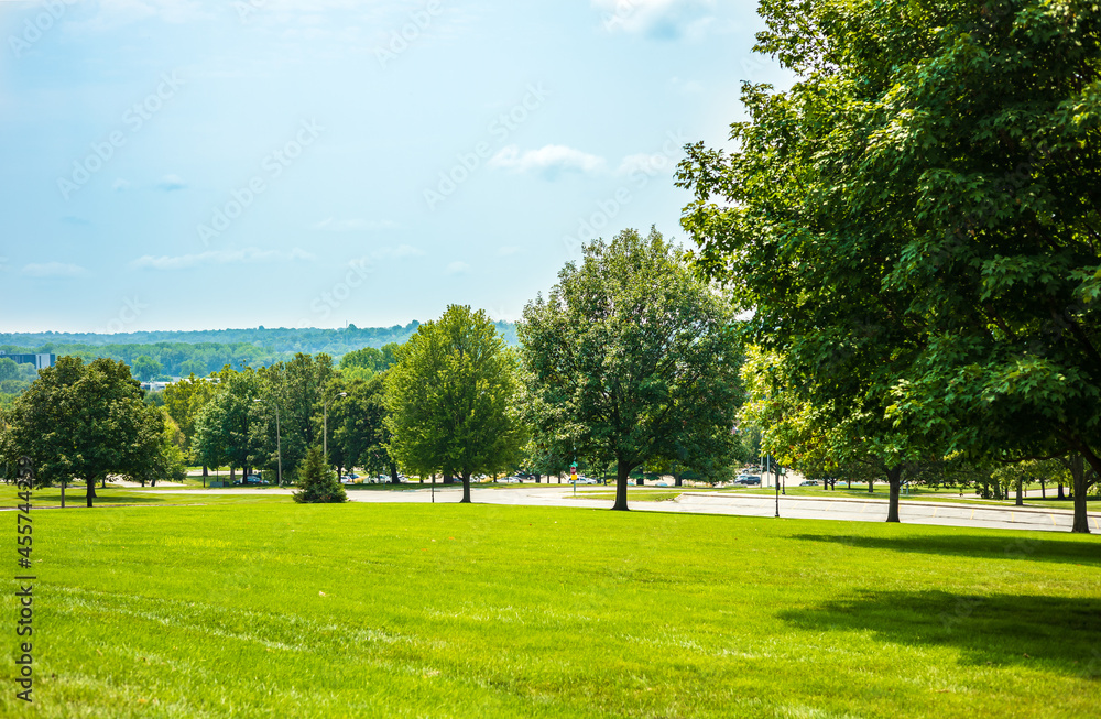 Scenic of green landscape, public outdoor park for leisure and picnic in summer. Greenery environment, lush field and trees and blue sky. Recreation and relaxation place with nature. Depth of field.