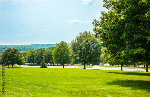 Scenic of green landscape, public outdoor park for leisure and picnic in summer. Greenery environment, lush field and trees and blue sky. Recreation and relaxation place with nature. Depth of field.