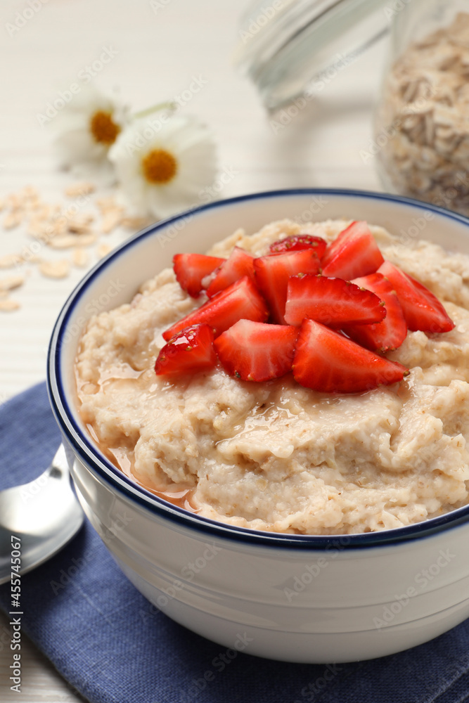 Tasty oatmeal porridge with strawberries served on table, closeup Tasty oatmeal porridge with strawberries served on table, closeup