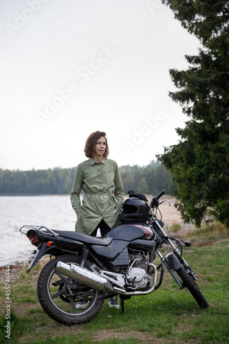 girl riding a motorcycle outdoors. Portrait of a confident woman on a beach background