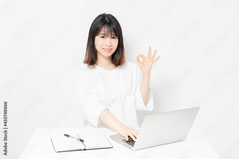 ノートパソコンを使いながらOKサインをする若い女性 ノートパソコンを使いながらOKサインをする若い女性
