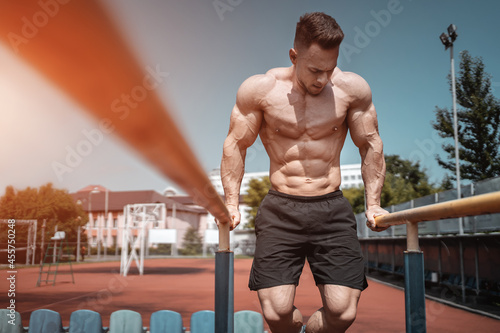 attractive muscular athlete man or bodybuilder pull up and exercising outdoor photo