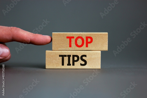 Top tips symbol. Concept words Top tips on wooden blocks on a beautiful grey background. Businessman hand. Business and Top tips concept, copy space.