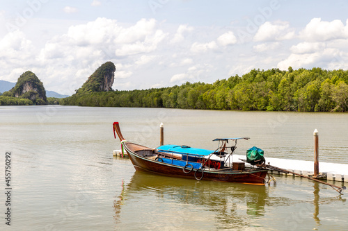 blue motor boat near the pier on the background of green mountains covered with jungle