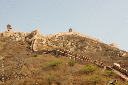 Slika na platnu The ramparts of the ancient Amer Fort rising above a green scrubland in the city of Jaipur in Rajasthan, India