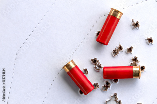 Foto Three shotgun cartridges are on a shot-torn perforated cardboard target