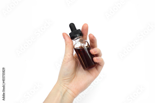 female hand holding glass cosmetic bottle with pipette isolated on white background