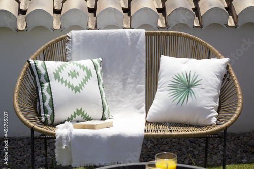 wicker sofa with two cushions and a white towel on a terrace
