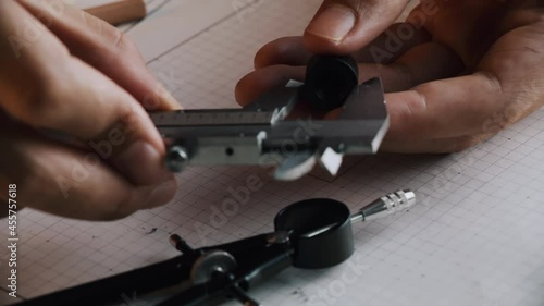 Hands of Engineer using vernier caliper to scale the black screw