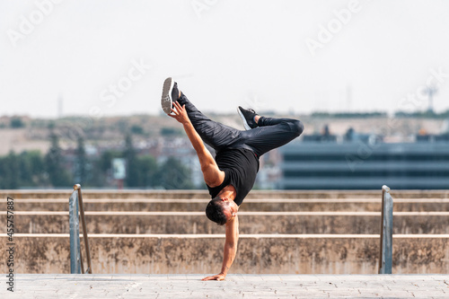 Break dancer performing a hand stand in park photo