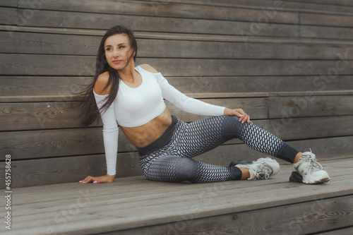 Woman in sportswear posing on the background of wooden steps.
