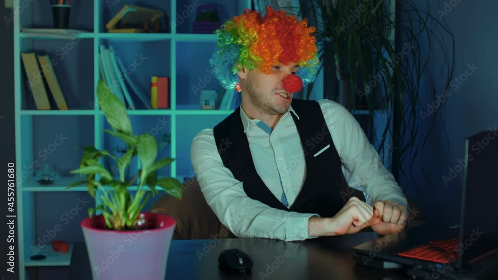 Young man in image of clown with closed eyes typing on keyboard. Funny