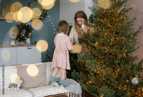 Happy woman with girl decorating Xmas tree photo