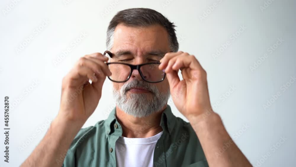 Friendly looking retired senior man taking off his glasses and smiling cheerfully while looking into the camera Friendly looking retired senior man taking off his glasses and smiling cheerfully while looking into the camera