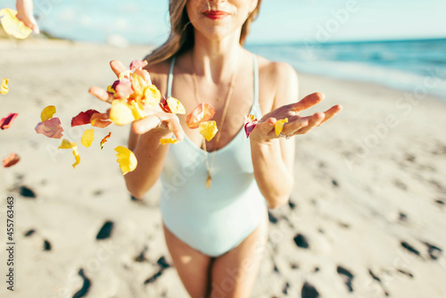 Woman releasing flower petals on a beach photo