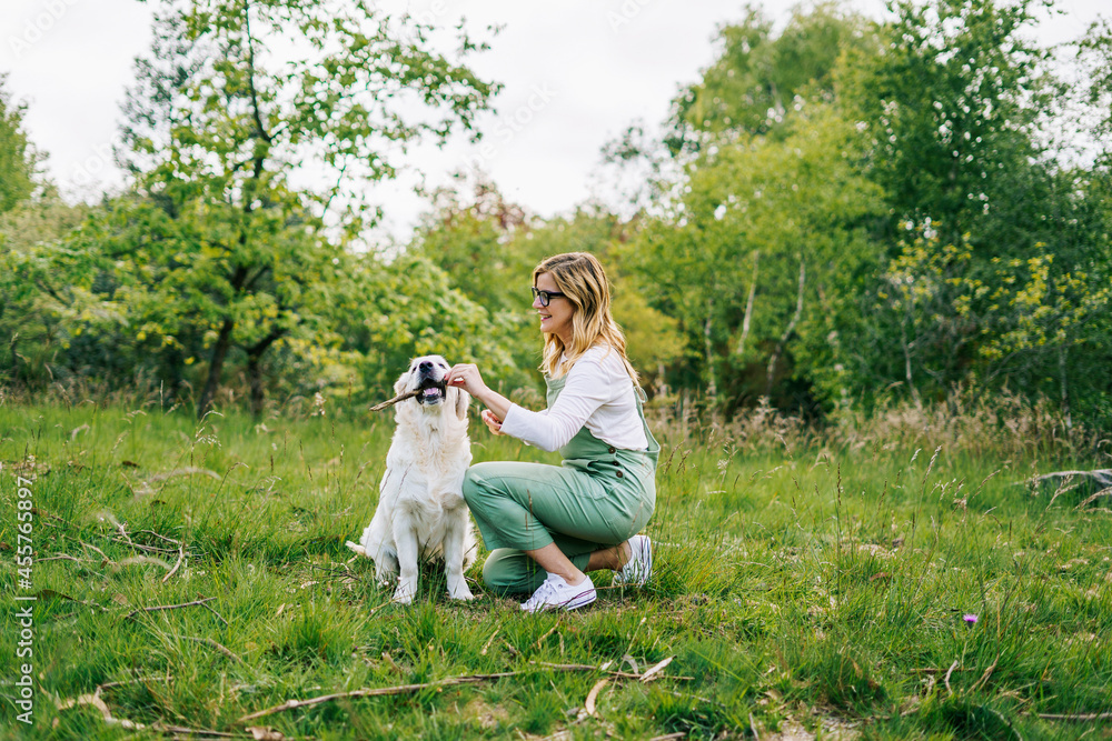 A woman plays with a stick with her dog in a park
A woman plays with a stick with her dog in a park
