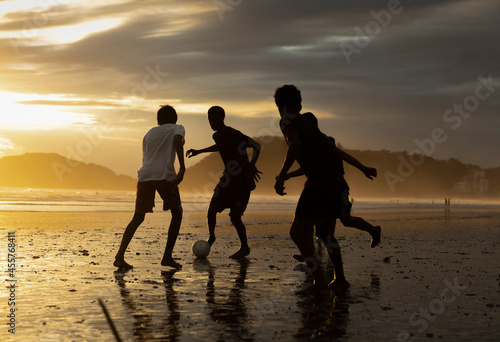 Group of Friends playing Beach football end of day photo