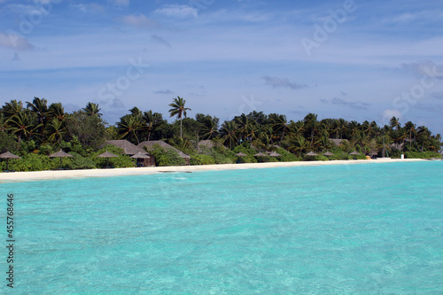 Villas with palm trees on white sandy beach beautiful scenery of Maldives island