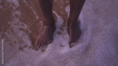 Pies descalzos en la orilla de la playa siendo cubierto por el oleaje photo