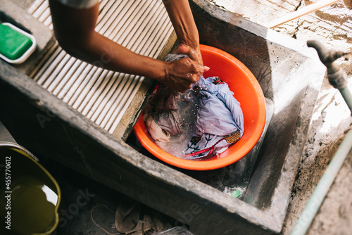 Faceless person doing laundry by hands in concrete reservoir photo