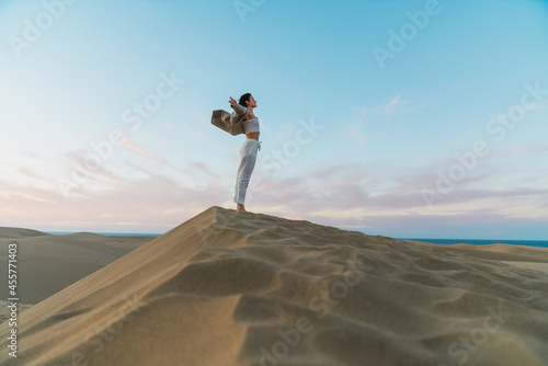 Woman standing on sand land and blue sky at sunset photo
