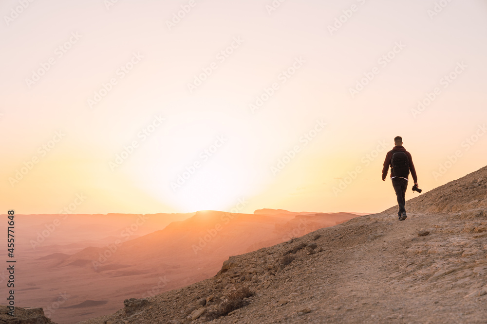 Man holding a camera walking during susnet.
