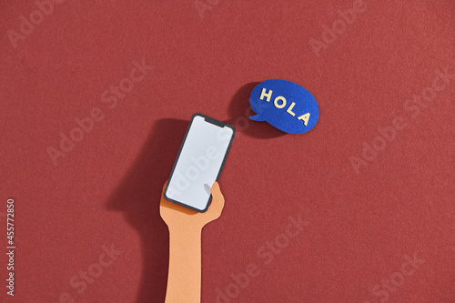 Mobile phone in hand and speech bubble, text hola photo