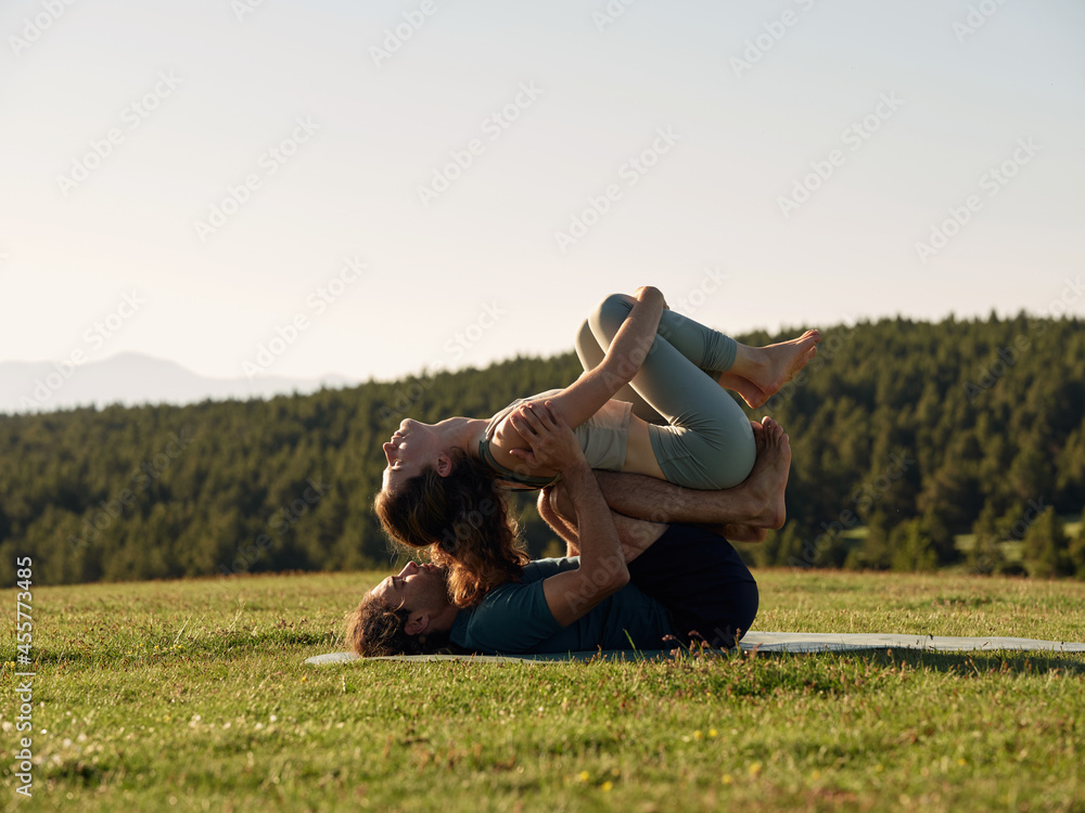 Relaxed couple stretching in acro yoga pose in nature Relaxed couple stretching in acro yoga pose in nature