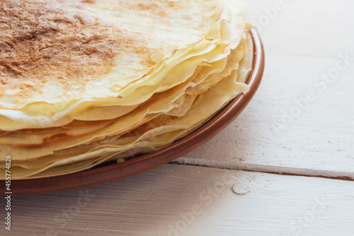 Crepes, thin pancakes on a plate on a white wooden table