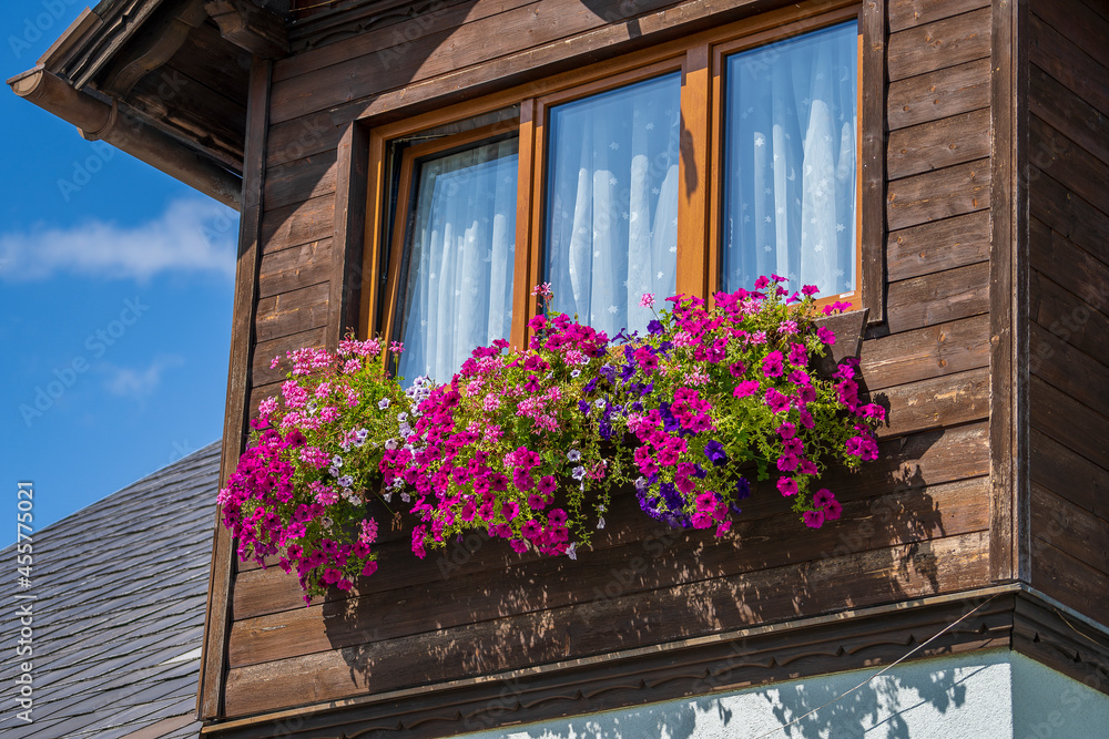 The wooden mezzanine of an old farm mountain house with colorfull flowers in Austria