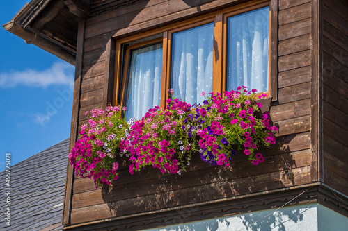 The wooden mezzanine of an old farm mountain house with colorfull flowers in Austria