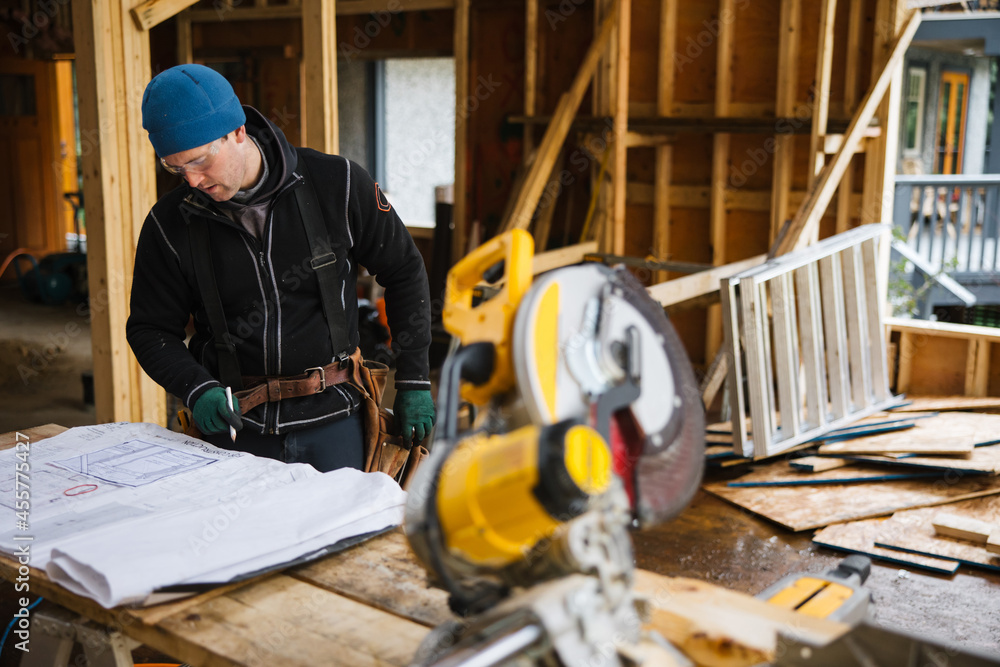 Carpenter reading construction plans on the job site in winter Carpenter reading construction plans on the job site in winter